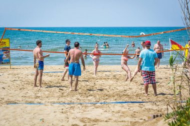 Side, Turkey - Haziran 2018: Kumlu bir plajın kıyısında voleybol oynayan mayo ve mayo giyen bir grup insan.