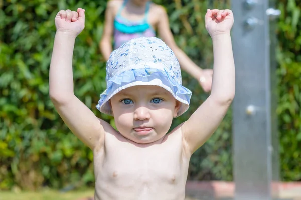 日焼け止めの青い目を持つ小さな赤ちゃんは、日光浴のために彼女の腕を上げます. — ストック写真