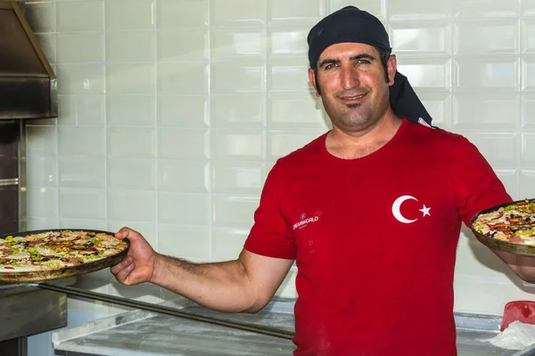 Side, Turkey - 1 Haziran 2018: Elinde pizzalarla kırmızı ayakkabılı bir Türk şefin portresi.