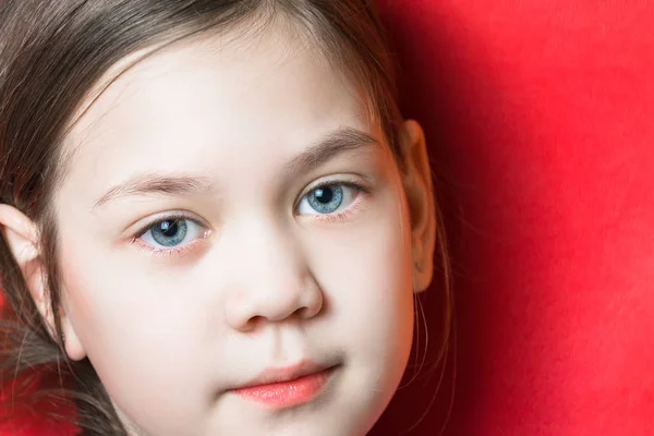Retrato de uma menina bonito em um fundo vermelho — Fotografia de Stock