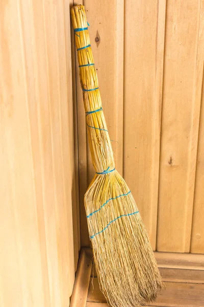 Yellow broom stands on a shelf in the corner of the bath — Stock Photo, Image