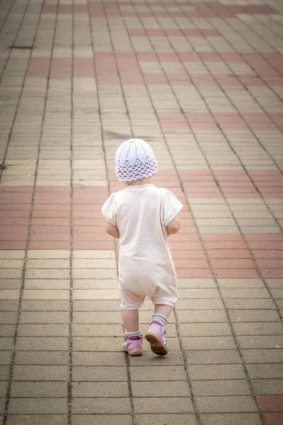 Nehir limanının rıhtımından asfalt yolun etrafında koşan beyaz takım elbiseli küçük bir çocuk.