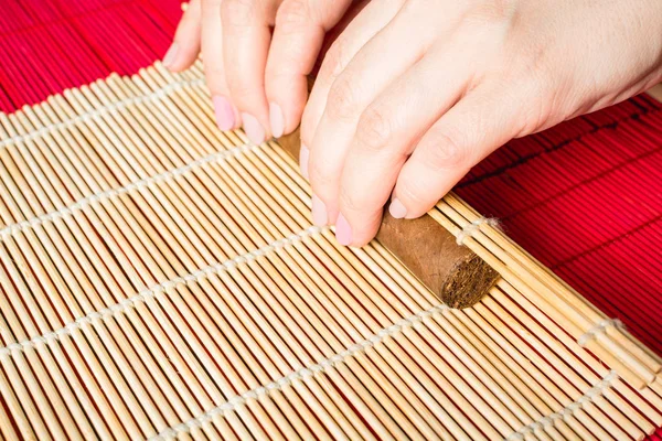 Female hands tightening homemade cigar with help bamboo mat, concept of how to make cigar