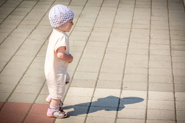 Un petit enfant en costume blanc qui court autour du chemin pavé depuis le quai du port fluvial — Photo