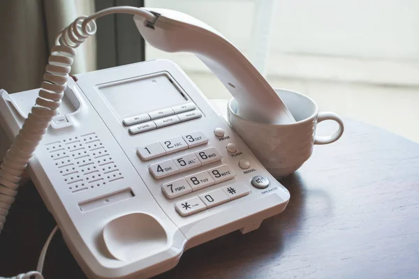 Tubo com fio do número de telefone de casa em círculo na mesa de madeira . — Fotografia de Stock