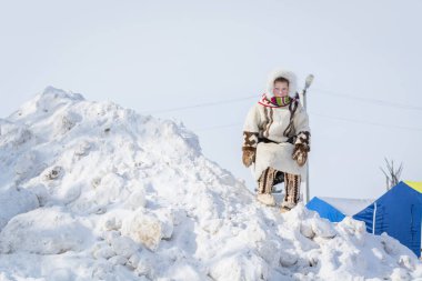 Russkinskaya, Rusya - 24 Mart 2018: Geyik derisi deri ve kürklerden yapılmış ulusal sibirya kıyafetleri giyen Taiga çocuğu, merkez meydandaki karlı dağa tırmandı. Reindeer çobanTatil.
