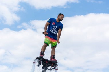 Side, Türkiye - 1 Haziran 2018: Yakışıklı tabaklanmış adam sineklikte duruyor ve bulutlarla mavi gökyüzüne uçuyor.