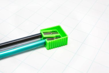 Kağıt beyaz bir levha üzerinde kalemsaç yeşil ve siyah kalemler.