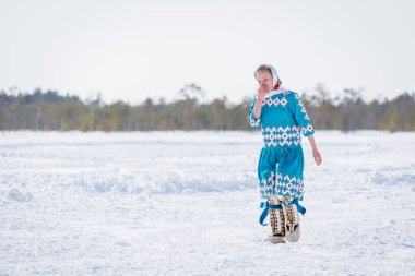 Russkinskaya, Rusya - 24 Mart 2018: Kuzeydeki ulusal giyimli Hanty kadın, kızlar arasındaki koşuda diğer katılımcıların gerisinde kaldı ve elini burnuyla sildi. Reindeer Bayramı