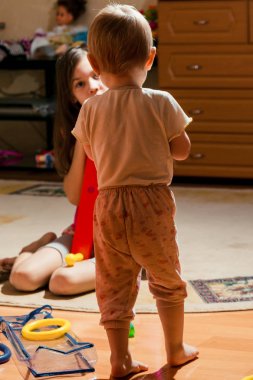 Çocuk ayağa kalkar ve kız kardeşine bakar.