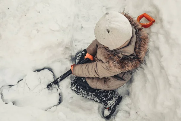 Çocuk karları kürekle tırmıklar.