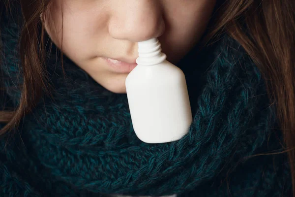 女孩与温暖的围巾在她的脖子上与小瓶从鼻塞滴. — 图库照片