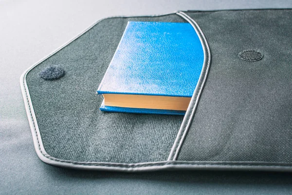 Синяя книга лежит в футляре с ноутбука — стоковое фото