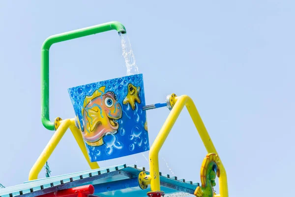 Side, Turkey - June 2018: Large bucket with fish and asterisk is poured with water from green pipe installed in pool for children. — Stock Photo, Image