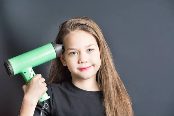 Beautiful girl dries hair with green hair dryer