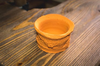 Ahşap masa üzerinde duran kırmızı kil pot