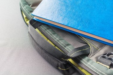Mavi kitap bir dizüstü bilgisayar çantası yatıyor
