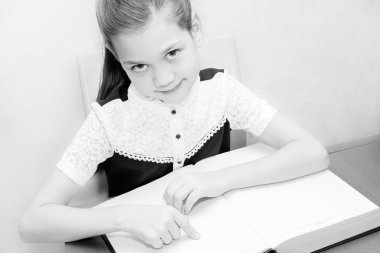 Güzel kız öğrenci masada bir kitap ile oturur