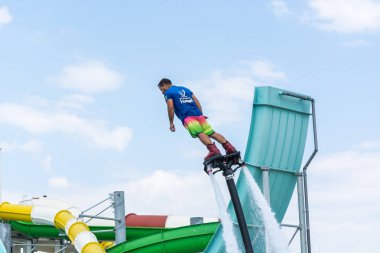 Side, Türkiye - 1 Haziran 2018: Yakışıklı tabaklanmış adam sineklikte duruyor ve bulutlarla mavi gökyüzüne uçuyor.