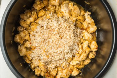 Yavaş ocakta pilav yapmak için uzun taneli pirinç ve tavuk parçaları döşeme.