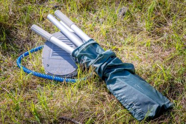 Pompanın yanındaki çimenlerin üzerinde yatan kesedeki kürekler.