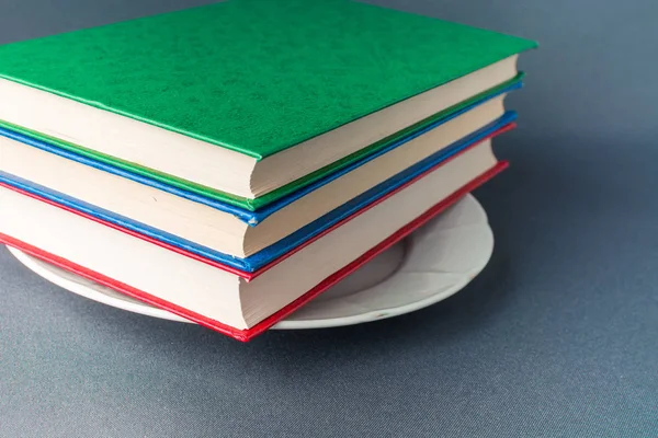 Стек різнокольорових книг лежить на білій тарілці — стокове фото
