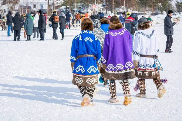 Russkinskaya, Ryssland-24 mars 2018: Khanty män i National Northern kläder gjorda av hjortskinn läder och päls gå längs den centrala gatan där semestern börjar. Ferie av renherderen. — Stockfoto