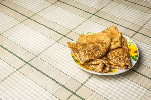 Pancake tipis yang dimasak dalam panci terletak di piring kecil di atas meja dapur . — Stok Foto