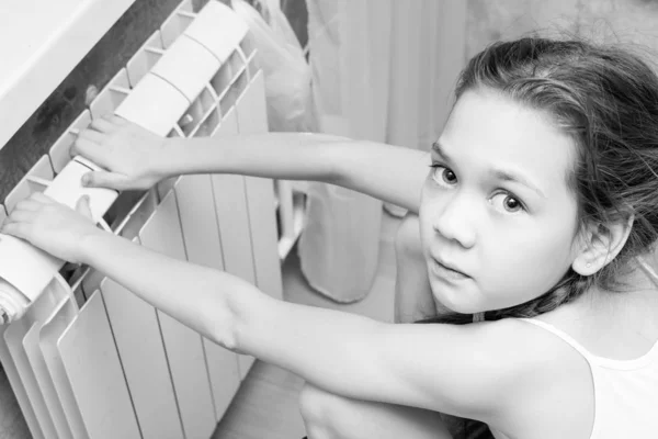 Beautiful child warms his hands at the battery — Stock Photo, Image