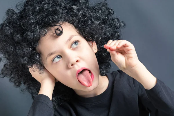 Belle fille dans une perruque bouclée noire montre la langue — Photo