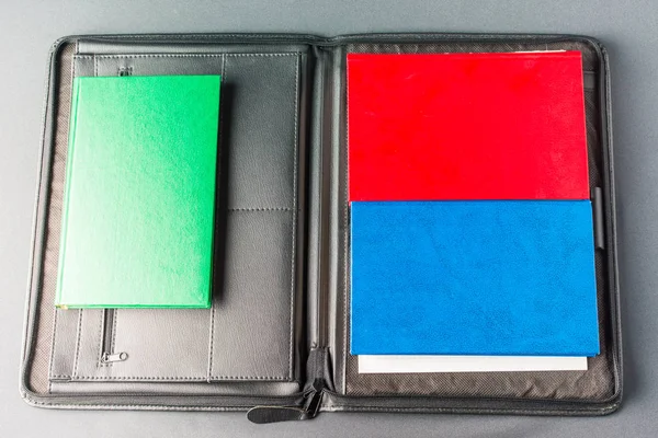 Stack of colorful books lies on a black leather folder — Stock Photo, Image