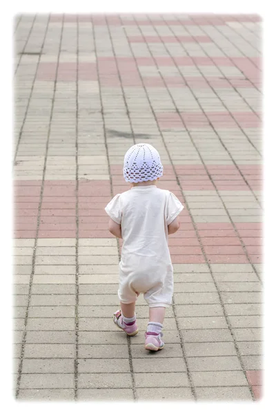 Un petit enfant en costume blanc qui court autour du chemin pavé depuis le quai du port fluvial — Photo