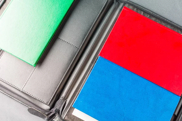 Stack of colorful books lies on a black leather folder — Stock Photo, Image