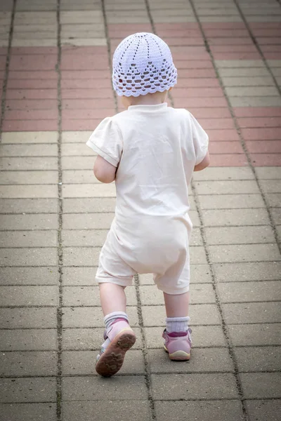 川港の岸壁から舗装された道を走り回る白いスーツを着た小さな子供 — ストック写真