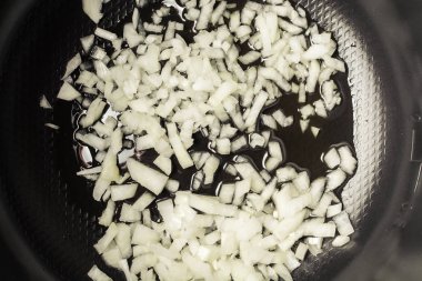 Dilimlenmiş soğan pişirme için multicooker kasede kızartılmış.