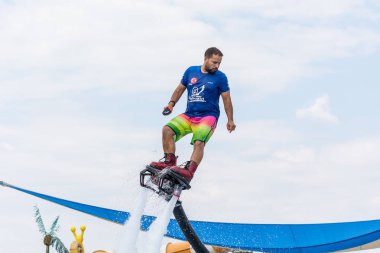 Side, Türkiye - 1 Haziran 2018: Yakışıklı tabaklanmış adam sineklikte duruyor ve bulutlarla mavi gökyüzüne uçuyor.