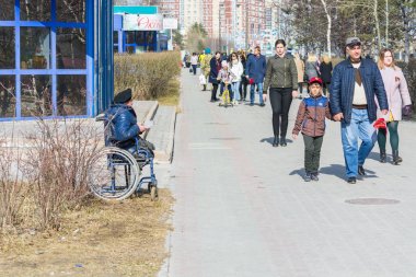 Surgut, Russia - MAY 9, 2018: The military disabled person with beret on head in carriage asks money from passersby of people. Holiday Victory Day May 9th. clipart