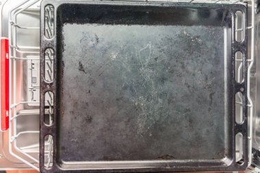 Büyük siyah fırın tepsisi bulaşık makinesinin alt bölmesinde yatıyor