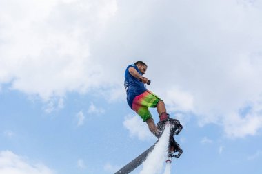 Side, Türkiye - 1 Haziran 2018: Yakışıklı tabaklanmış adam sineklikte duruyor ve bulutlarla mavi gökyüzüne uçuyor.