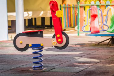 Parkta oyun alanında çocuklar için motosiklet şeklinde baharda Salıncak.