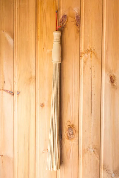 Бамбуковая метла, висящая на стене в сауне — стоковое фото