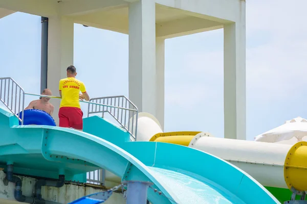 Côté, Turquie - Juin 2018 : L'instructeur enseigne à un homme avec un tube les règles de conduite d'un toboggan aquatique dans le parc aquatique . — Photo