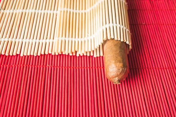 Кудрявая сигара, завернутая в красивый бамбуковый коврик. — стоковое фото