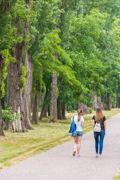 Krasnodar, Rusland-7 juni 2018: mooie meisjes met stads rugzakken wandelen langs steeg in Park. — Stockfoto