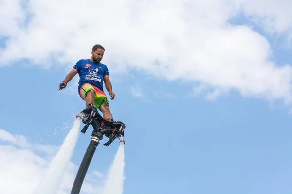 SIDE, TURCHIA - 1 GIUGNO 2018: Il bell'uomo abbronzato sta sul flyboard e vola contro il cielo blu con le nuvole . — Foto Stock