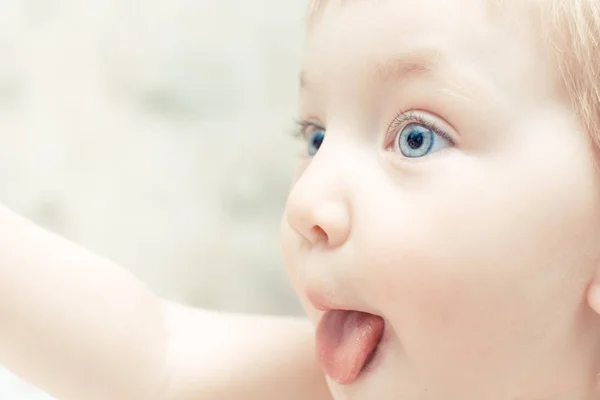 Mignon enfant avec les yeux bleus a collé sa langue en prévision de manger . — Photo