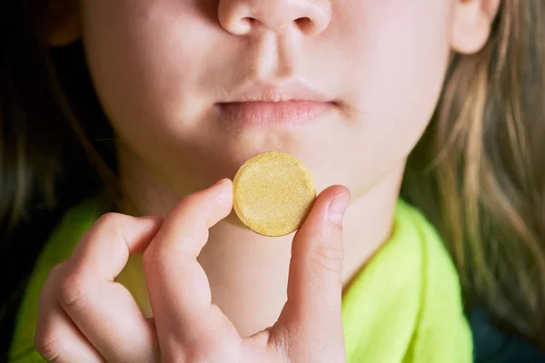 Больная девушка держит большую желтую таблетку во рту, чтобы принять . — стоковое фото