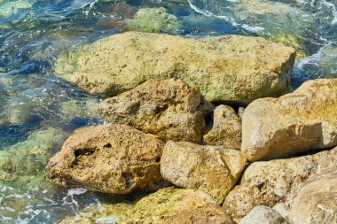 Sahil mavi deniz yakınında keskin taşlarla döşenmiştir