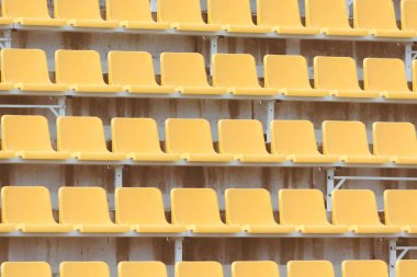 Futbol tribününde taraftarlar için sarı boş koltuklar.