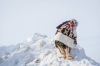 Russkinskaya, Rusya - 24 Mart 2018: Geyik derisi ve kürkten yapılmış ulusal sibirya kıyafetleri içinde stoklu çocuk, merkez meydandaki karlı dağa tırmanıyor. Reindeer çobanTatil.